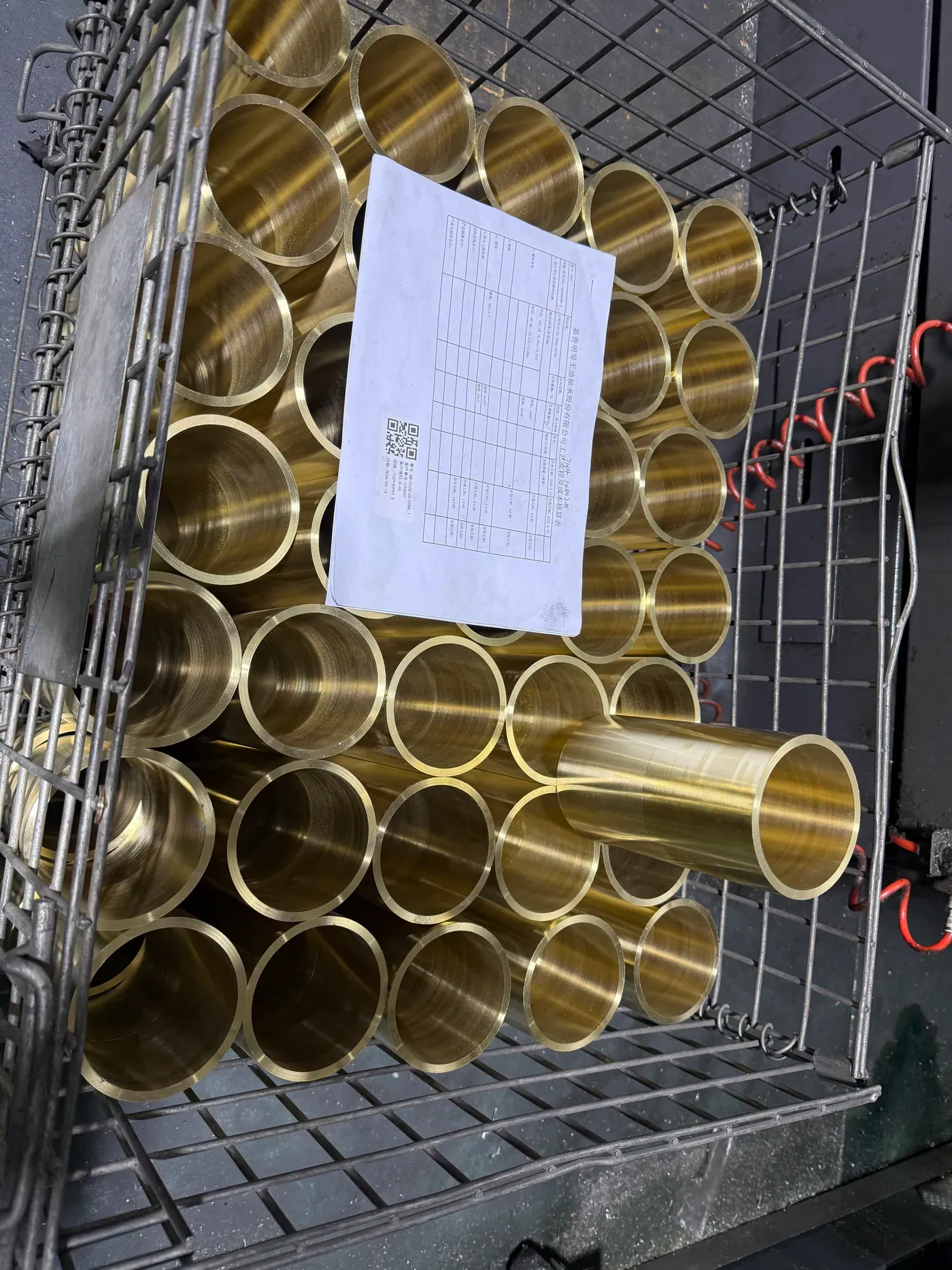 Bronze sleeve bushings of several diameters in a bin with a job label