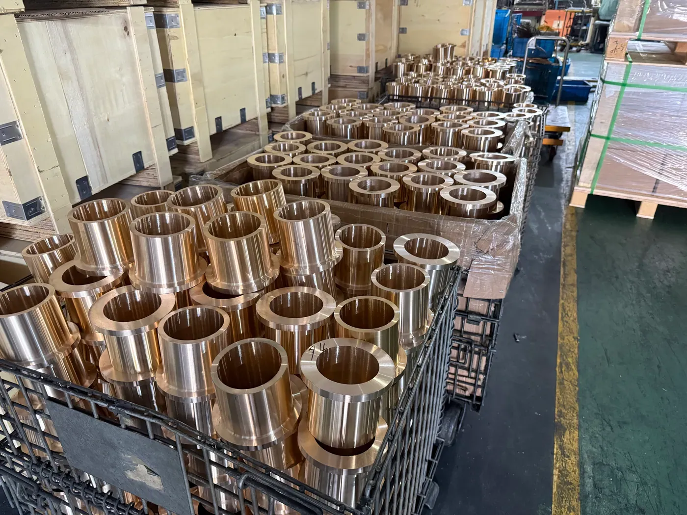 A batch of machined cast bronze sleeve bushings in a wire cage after turning