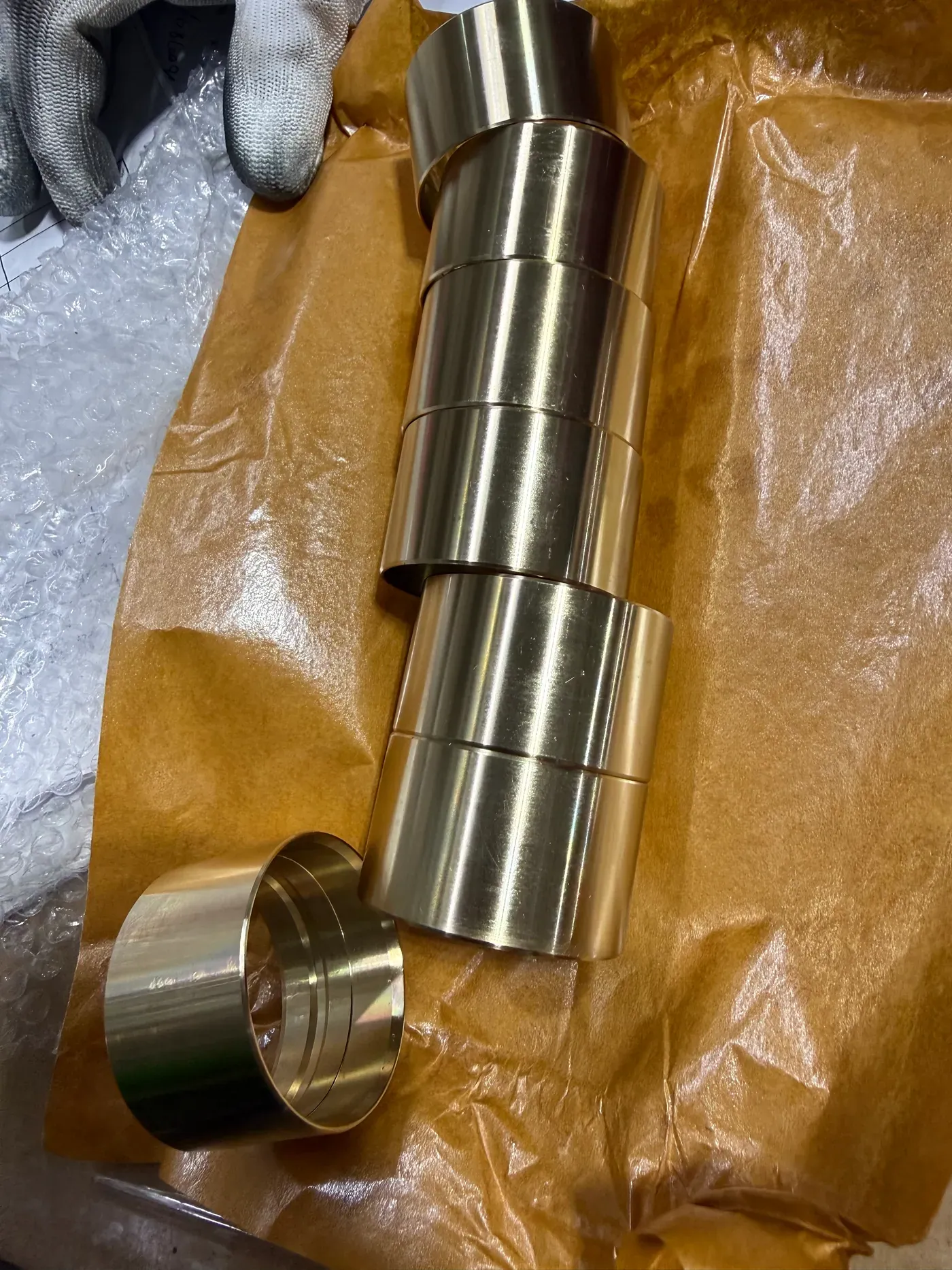 Small cast bronze bushings on kraft paper, freshly machined