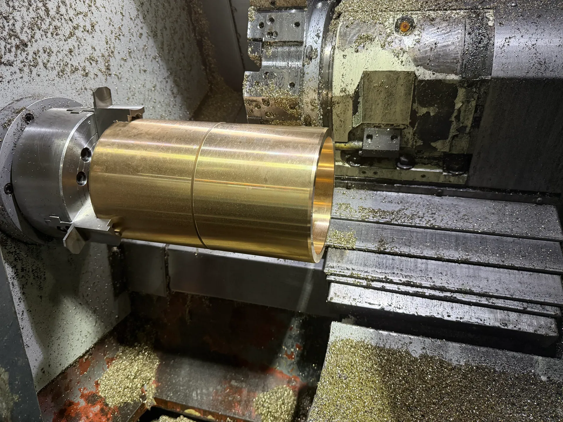 Cast bronze bar being turned on a CNC lathe at Slidura
